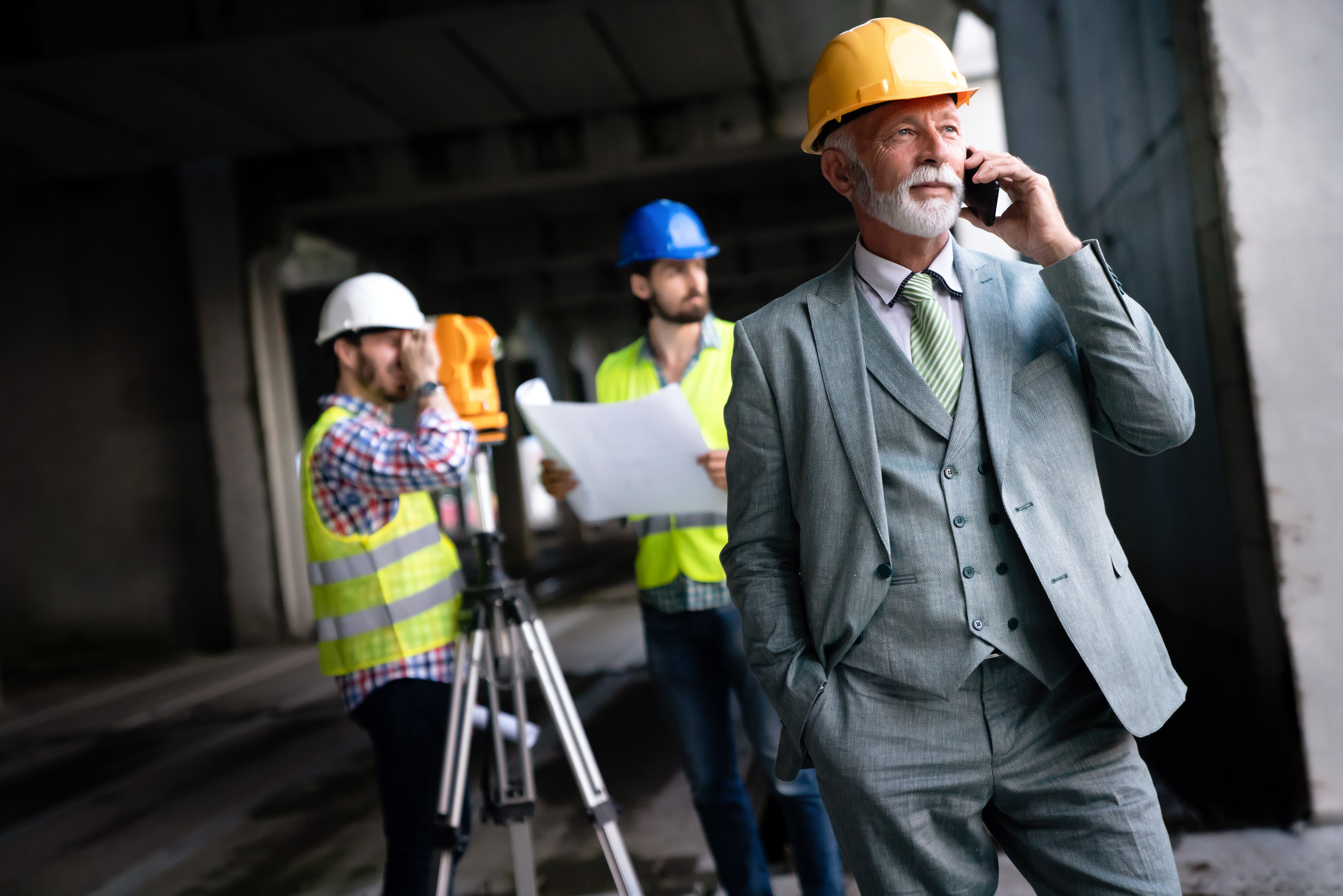 A construction executive reviewing leadership transition plans with team members at a job site, emphasizing the importance of crisis-proof succession planning.